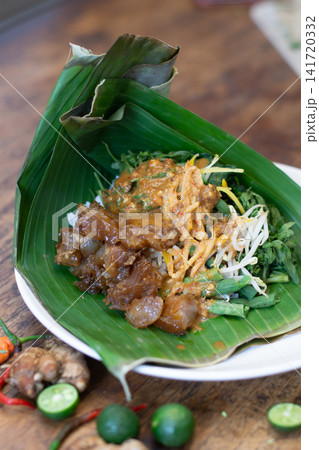 Indonesian pecel koyor with cow tendon and vegetables in peanut sauce served on banana leaf. Southeast Asian traditional cuisine. Indonesian pecel koyor with cow tendon and vegetables in peanut sauce served on banana leaf. Southeast Asian traditional cuisine. 141720332