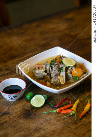 Sop buntut Indonesian oxtail soup with clear broth, vegetables and lime garnish. Traditional Southeast Asian cuisine Sop buntut Indonesian oxtail soup with clear broth, vegetables and lime garnish. Traditional Southeast Asian cuisine 141720337
