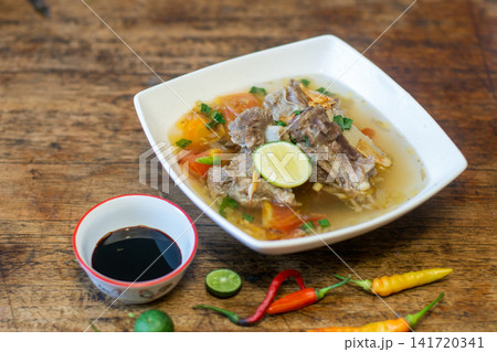 Sop buntut Indonesian oxtail soup with clear broth, vegetables and lime garnish. Traditional Southeast Asian cuisine Sop buntut Indonesian oxtail soup with clear broth, vegetables and lime garnish. Traditional Southeast Asian cuisine 141720341