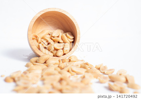 Peanuts in a wooden cup rest on a white background, creating a warm and rustic food-themed scene. Peanuts in a wooden cup rest on a white background, creating a warm and rustic food-themed scene. 141720492