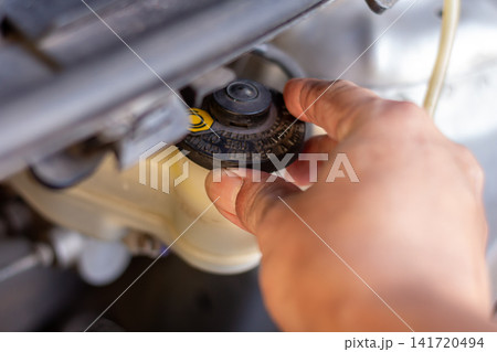 Checking brake fluid reservoir cap to ensure safe braking system performance and proper maintenance. Checking brake fluid reservoir cap to ensure safe braking system performance and proper maintenance. 141720494