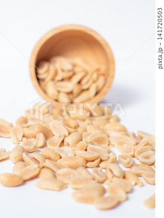 Peanuts in a wooden cup rest on a white background, creating a warm and rustic food-themed scene. Peanuts in a wooden cup rest on a white background, creating a warm and rustic food-themed scene. 141720503