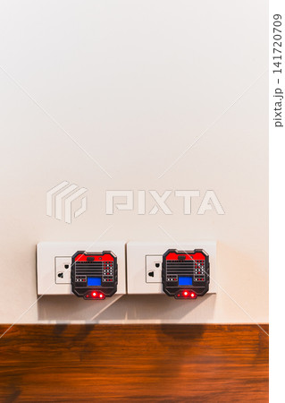 Two digital socket testers plugged into wall outlets to check electrical wiring. 141720709