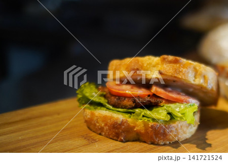 Rustic Gourmet Sandwich with Artisan Bread Tomato Lettuce and Grilled Patty on Wooden Board Rustic Gourmet Sandwich with Artisan Bread Tomato Lettuce and Grilled Patty on Wooden Board 141721524