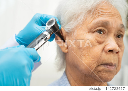 Otolaryngologist or ENT physician doctor examining senior patient ear with otoscope, hearing loss problem. Otolaryngologist or ENT physician doctor examining senior patient ear with otoscope, hearing loss problem. 141722627