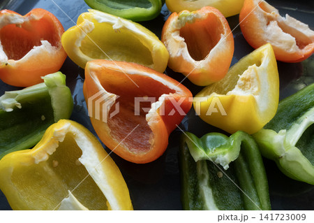 Colorful bell pepper halves preparing for cooking on dark background Colorful bell pepper halves preparing for cooking on dark background 141723009