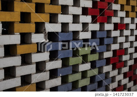 Abstract colorful brick wall with an openwork geometric pattern of painted bricks and square openings Abstract colorful brick wall with an openwork geometric pattern of painted bricks and square openings 141723037