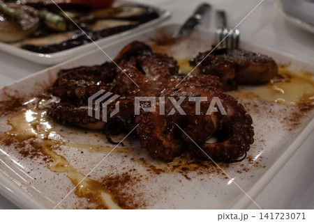Grilled octopus served with olive oil and paprika on a white plate Grilled octopus served with olive oil and paprika on a white plate 141723071