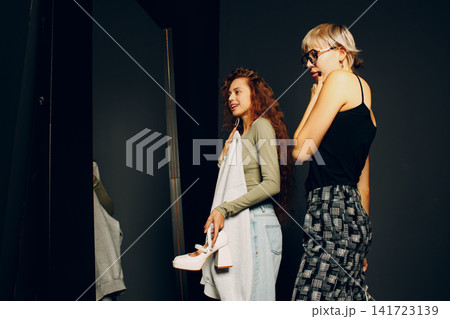 Beautiful young woman stylist designer helping choose clothes to customer client Beautiful young woman stylist designer helping choose clothes to customer client 141723139