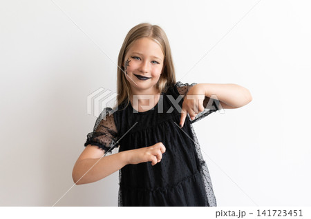Girl in witch costume pointing down on white background Girl in witch costume pointing down on white background 141723451