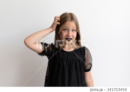 Girl in witch costume looking confused and scratching head on white background Girl in witch costume looking confused and scratching head on white background 141723459