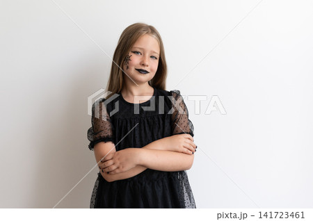 Girl child in witch costume with arms crossed smiling on white background Girl child in witch costume with arms crossed smiling on white background 141723461