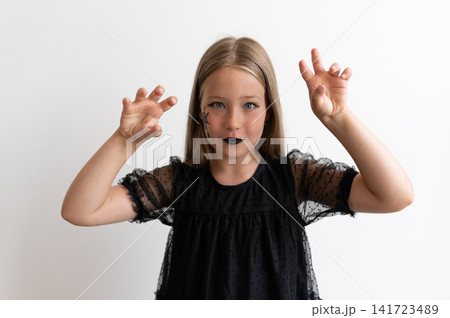 Girl in witch costume making monster claws on white background 141723489