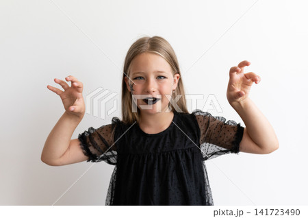 Playful girl in witch costume making scary hands on white background 141723490