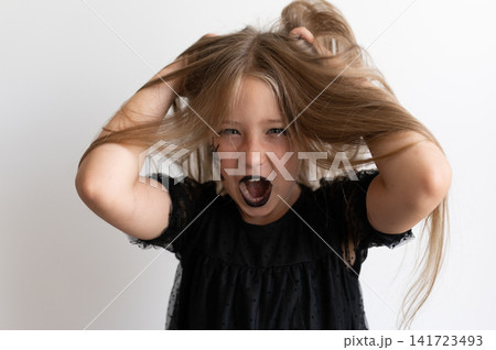 Girl in witch costume roaring and holding her hair on white background 141723493