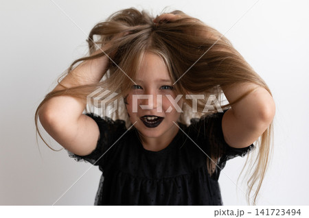 Girl in witch costume playing with her hair on white background Girl in witch costume playing with her hair on white background 141723494