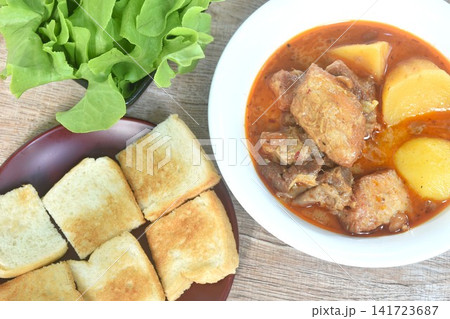 pork curry or Mussamun Indian food with slice potato on bowl eat couple fresh green oak salad and grilled butter toast bread pork curry or Mussamun Indian food with slice potato on bowl eat couple fresh green oak salad and grilled butter toast bread 141723687
