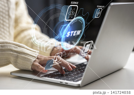 Close-up of a female using a stylus to interact with a digital STEM interface hovering above a laptop, representing science, technology, engineering, and mathematics education. STEM education concept Close-up of a female using a stylus to interact with a digital STEM interface hovering above a laptop, representing science, technology, engineering, and mathematics education. STEM education concept 141724038