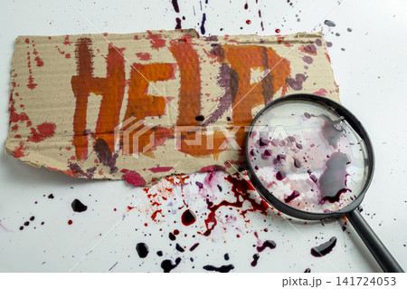 A close-up shot of a piece of cardboard with the word HELP written in red blood splatter, with a magnifying glass placed over it against a white, splattered background. Concept of Halloween A close-up shot of a piece of cardboard with the word HELP written in red blood splatter, with a magnifying glass placed over it against a white, splattered background. Concept of Halloween 141724053
