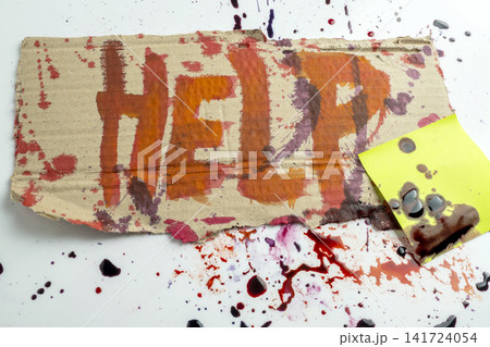 A piece of cardboard with the word HELP painted in red, splattered with dark red blood, and a sticky note on a white background, representing a conceptual emergency or cry. Concept of Halloween A piece of cardboard with the word HELP painted in red, splattered with dark red blood, and a sticky note on a white background, representing a conceptual emergency or cry. Concept of Halloween 141724054