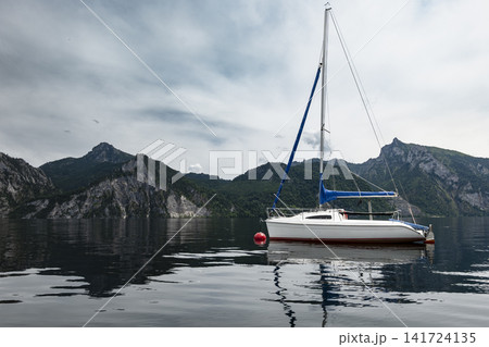 Sailboat on an alpine lake with mountain landscape, illustrating European alpine vacation by the water and summer atmosphere. 141724135