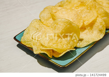 golden potato chips on a turquoise rectangular plate golden potato chips on a turquoise rectangular plate 141724499