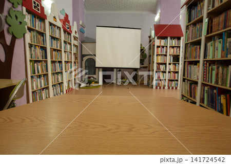 Sunny and inviting children's library with colorful bookshelves and a presentation screen Sunny and inviting children's library with colorful bookshelves and a presentation screen 141724542