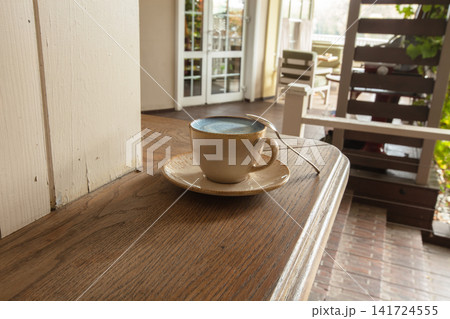 Cup of coffee on a wooden table in a cozy cafe during the morning hours Cup of coffee on a wooden table in a cozy cafe during the morning hours 141724555