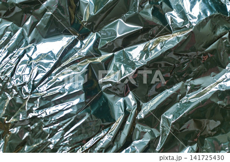 foil texture in teal color with crumpled reflective surface and sharp folds, 141725430