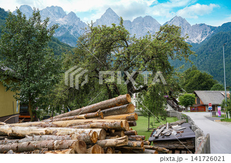 Stacked firewood and village houses in Kranjska Gora, Slovenia, with the rocky Julian Alps in the background, showing everyday alpine life and strong sense of place Stacked firewood and village houses in Kranjska Gora, Slovenia, with the rocky Julian Alps in the background, showing everyday alpine life and strong sense of place 141726021