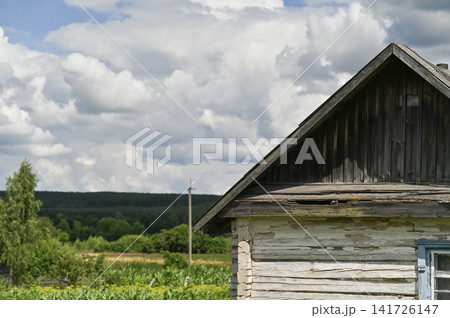 House stands in rural landscape with wooden wall and cloudy sky. House stands in rural landscape with wooden wall and cloudy sky. 141726147