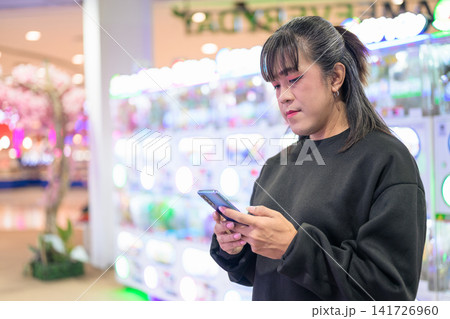 Asian Woman Texting on Smartphone in Arcade Alleyway Asian Woman Texting on Smartphone in Arcade Alleyway 141726960