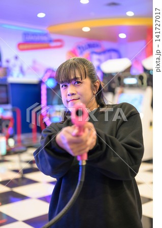 Front Perspective of Woman Aiming Pink Arcade Gun at Lens Front Perspective of Woman Aiming Pink Arcade Gun at Lens 141727017
