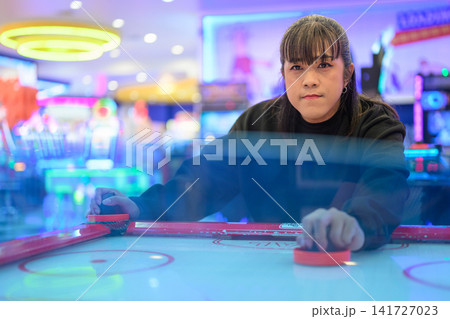 Front View of Woman Playing Air Hockey Game in Arcade 141727023