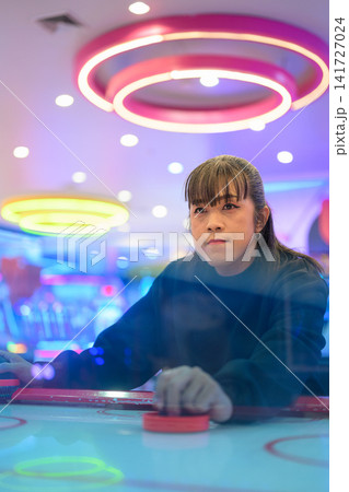 Moody Portrait of Woman Playing Air Hockey in Arcade Moody Portrait of Woman Playing Air Hockey in Arcade 141727024