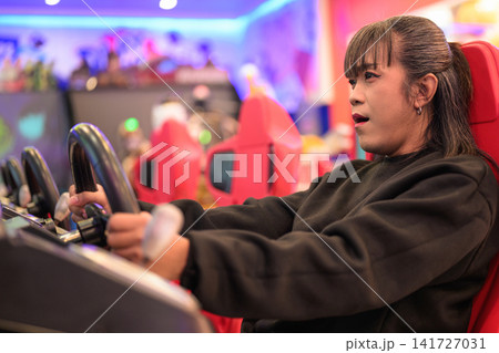 Side Profile of Woman Playing Driving Arcade Game Side Profile of Woman Playing Driving Arcade Game 141727031