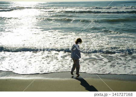 Child Walking Along the Beach with Gentle Waves Child Walking Along the Beach with Gentle Waves 141727168