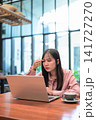 Thoughtful Asian Woman Touching Head while Looking at Laptop 141727270