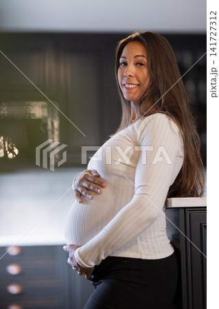 Joyful pregnant woman in a home setting showcasing positive moods 141727312