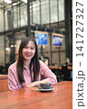 Portrait of a Confident Asian Woman Sitting in a Cafe with a Cup of Coffee 141727327