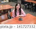 High Angle Portrait of a Smiling Asian Woman in a Cafe with a Cup of Coffee 141727332