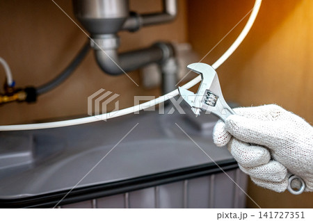 Plumber hand with glove fixing pipe connection with adjustable wrench 141727351