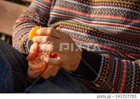 Person peeling a fresh orange for a healthy snack 141727783