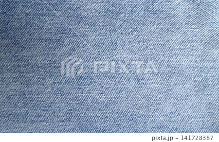 Close up of light blue denim with a characteristic diagonal twill weave, lighter and darker blue threads interwoven for a faded, speckled look. 141728387