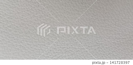 Top down close up of white or off-white grained leather with a consistent surface of small, irregular raised bumps and depressions characteristic of natural hide Top down close up of white or off-white grained leather with a consistent surface of small, irregular raised bumps and depressions characteristic of natural hide 141728397