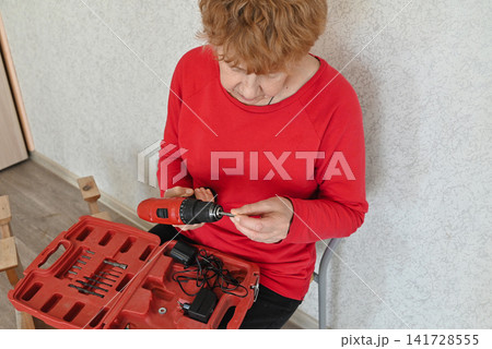 Woman working with tools in her home during daylight Woman working with tools in her home during daylight 141728555