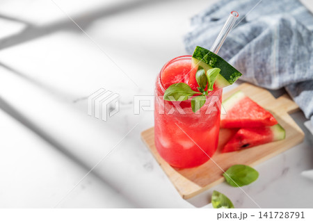 A watermelon lemonade or mojito with ice and basil in a glass on a marble background A watermelon lemonade or mojito with ice and basil in a glass on a marble background 141728791