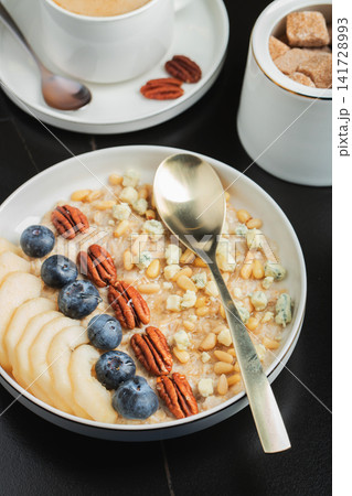 Oatmeal. Bowl of oatmeal porridge with blackberry, bananas and chia seeds on gray concrete old table background. Top view in flat lay style. Natural ingredients. Hot healthy breakfast and diet food Oatmeal. Bowl of oatmeal porridge with blackberry, bananas and chia seeds on gray concrete old table background. Top view in flat lay style. Natural ingredients. Hot healthy breakfast and diet food 141728993