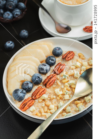 Oatmeal. Bowl of oatmeal porridge with blackberry, bananas and chia seeds on gray concrete old table background. Top view in flat lay style. Natural ingredients. Hot healthy breakfast and diet food Oatmeal. Bowl of oatmeal porridge with blackberry, bananas and chia seeds on gray concrete old table background. Top view in flat lay style. Natural ingredients. Hot healthy breakfast and diet food 141728995