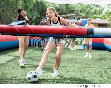 Group playing human table football with people holding bars in amusement park 141729059